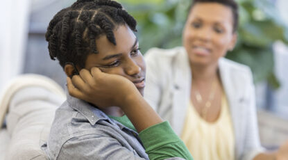 Depressed teenager with mother, stock photo