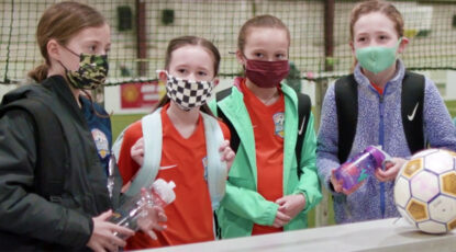 Girls in masks prepare to play soccer