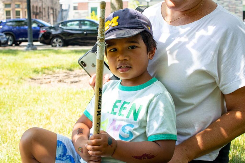 A young boy in Michigan cap holds a drumstick