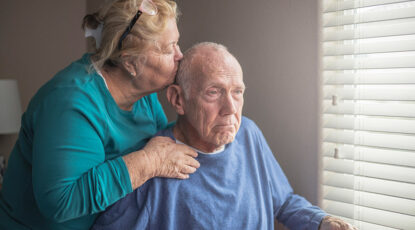 An elderly couple gazes out the window.