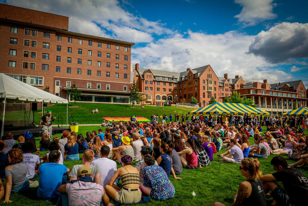 Students sit on the lawn to hear speakers at Gay Pride