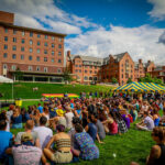 Students sit on the lawn to hear speakers at Gay Pride