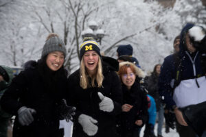 Snowball fight on the Diag 2023. Three girls laugh.