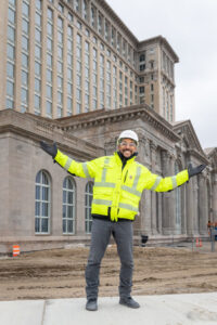 Environmental portrait of alumnus Manuel Martinez, supervising construction in a hard hat and yellow jacket, at the Michigan Central Station renovation project in Detroit.