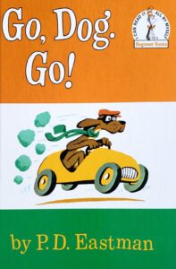 The childrens' book "Go, Dog. Go!" The cover is orange, white, and green, and a dog is driving a car.