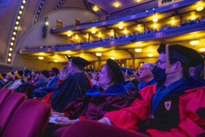 Faculty in full PhD regalia sit in Hill Auditorium watching President Ono's inauguration