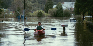 Ricky Rood in a kayak during flood. Houses and mailboxes underwater.