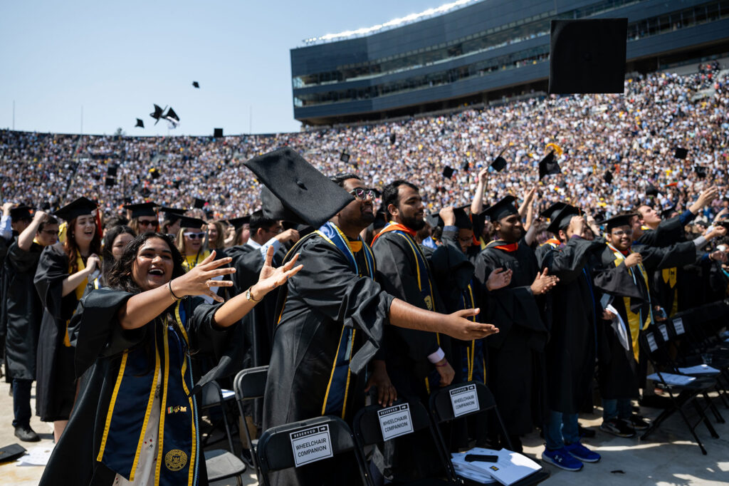 Students toss graduation caps in the air.