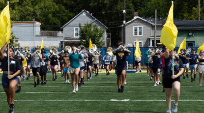 Michigan Marching band practices at Elbel with yellow flags.