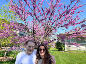 Father and daughter, Raoul and Shirli Kopelman, embrace beneath a pink, flowering tree.