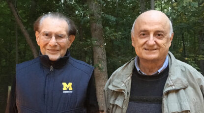 Two caucasian men, Raoul Kopelman and his mentee Panos Agryakis, stand side by side with trees behind them.