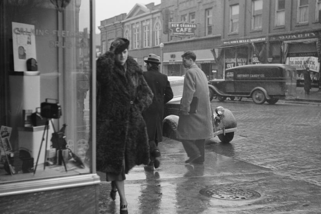 Black and white image of a woman walking on a rainy street in Ann Arbor, circa 1937.