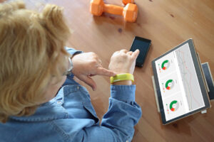 Woman wearing fitness tracker touches the tracker on her wrist while reviewing data and graphs on an iPad.