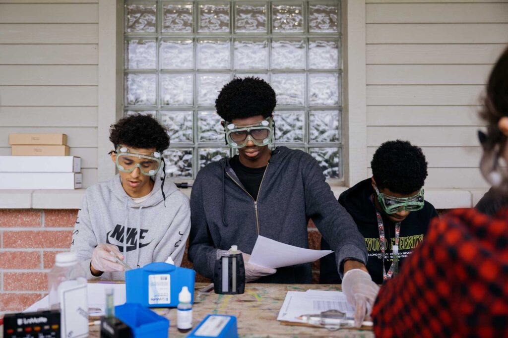 Middle school students wearing science goggles work in a lab as part of the Environmental Health Research-to-Action Academy.