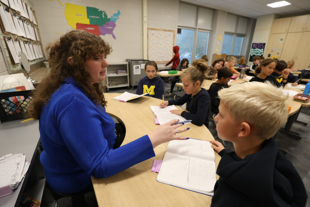 A young woman sits at a table in a classroom of young children in a fourth-grade class at Ada Vista Elementary School near Grand Rapids, Michigan.