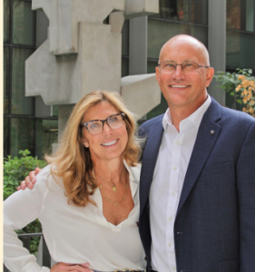 Two caucasian people, middle-age, stand together with arms around each other. They recently discovered they were siblings having attended dental school together and not knowing it.