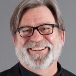 Headshot of a smiling caucasian man who writes for Michigan Today. He is beared and wearing glasses.