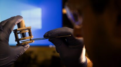 Extreme closeup of small gadget being held by gloved hands. The U-M discovery is a new water purification technology that helps turn seawater into drinking water without tons of chemicals.