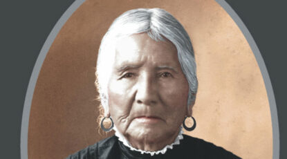 Portrait of Native American woman with white hair, hoop earrings, high collar.