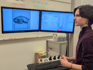 Woman in lab reviews images on a computer screen.