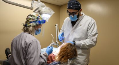 Two dentists work on a patient.