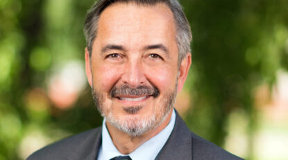 Headshot of caucasian-looking man, UM-Dearborn's Dominic Grasso, with salt-and-pepper hair, a beard, and a pleaseant smile. He is new interim president of U-M.