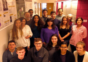 Team of researcher clusters in the hallway outside a lab.