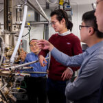 Researchers cluster around equipment in a U-M lab.