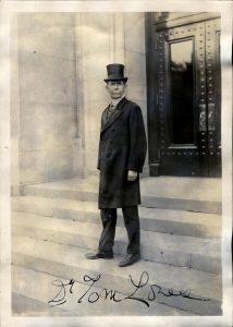 Image of caucasian man with a mustche, circa 1920, dressed in formal wear with top hat and tie.