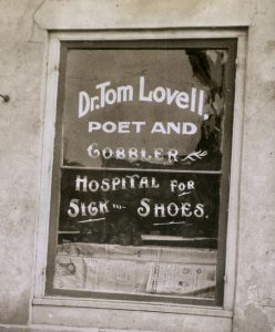 A storefront sign for a shoe repair shop on Huron Street in Ann Arbor, circa 1920, stating "Dr. Tom Lovell, poet and cobbler, hospital for sick shoes."