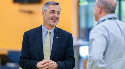 U-M President Domenico Grasso speaks to a man who is seen from behind.