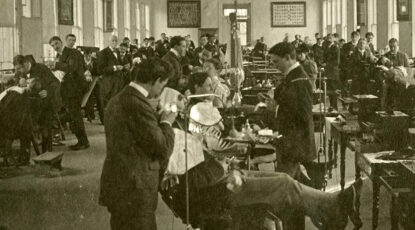 University of Michigan dental school circa 1908. Sepia-toned image of large room featuring several dental stations as doctors work on patients.