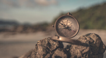 Compass sits atop a rock on a barren landscape.
