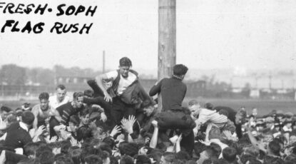 Black and white image, dated 1915, shows a crowd of rowdy University of Michigan freshmen and sophomores competing to climb a greased pole.