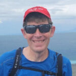 Caucasian man in red ball cap and sunglasses.