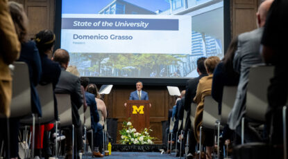 University of Michigan president presents from a podium during the 2025 State of the University address.