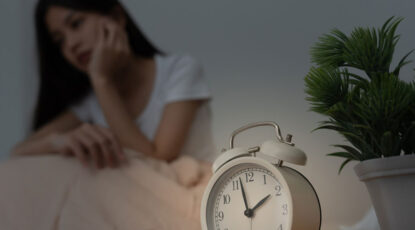 Image shows sleepless woman with alarm clock.