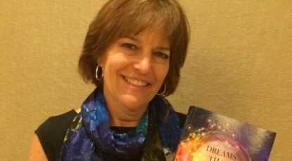 Smiling woman holds book about dreams.
