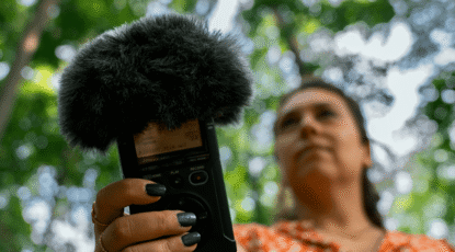 Woman holds microphone to record sounds in Nichols Arboretum at U-M in Ann Arbor.