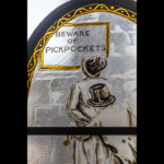 The crime is larceny: A man is pickpocketed as he reads a sign that says "Beware of Pickpockets."