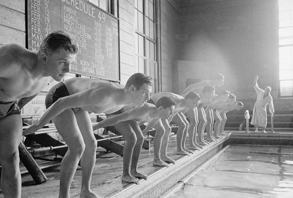 Lineup of young men in bathing suits perches at edge of swimming pool preparing to jump in. Black and white, University of Michigan, 1949. (Image credit: Stanley Kubrick, Look magazine photograph collection, Library of Congress.)
