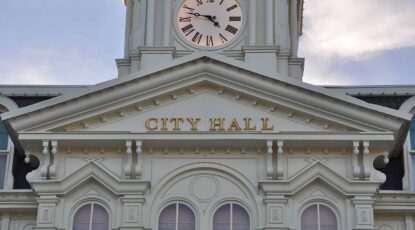 Front view of a government building with clock. Building reads: City Hall.