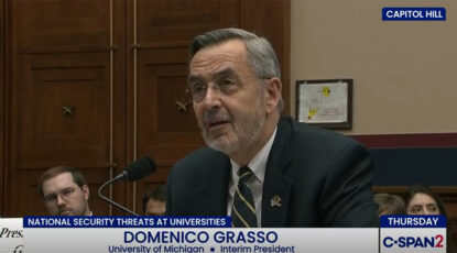 University of Michigan President Domenico Grasso testifies before Congress in March 2026. He is a silver-haired man wearing glasses, seated before a microphone, wearing a striped tie and dark suit.