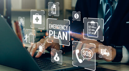 Stock photo shows hands on a keyboard surrounded by symbols regarding emergencies, SOS, plans, etc.