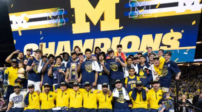 2026 Michigan Men's Basketball team assembles for a post-victory photo with NCAA. champion signage.