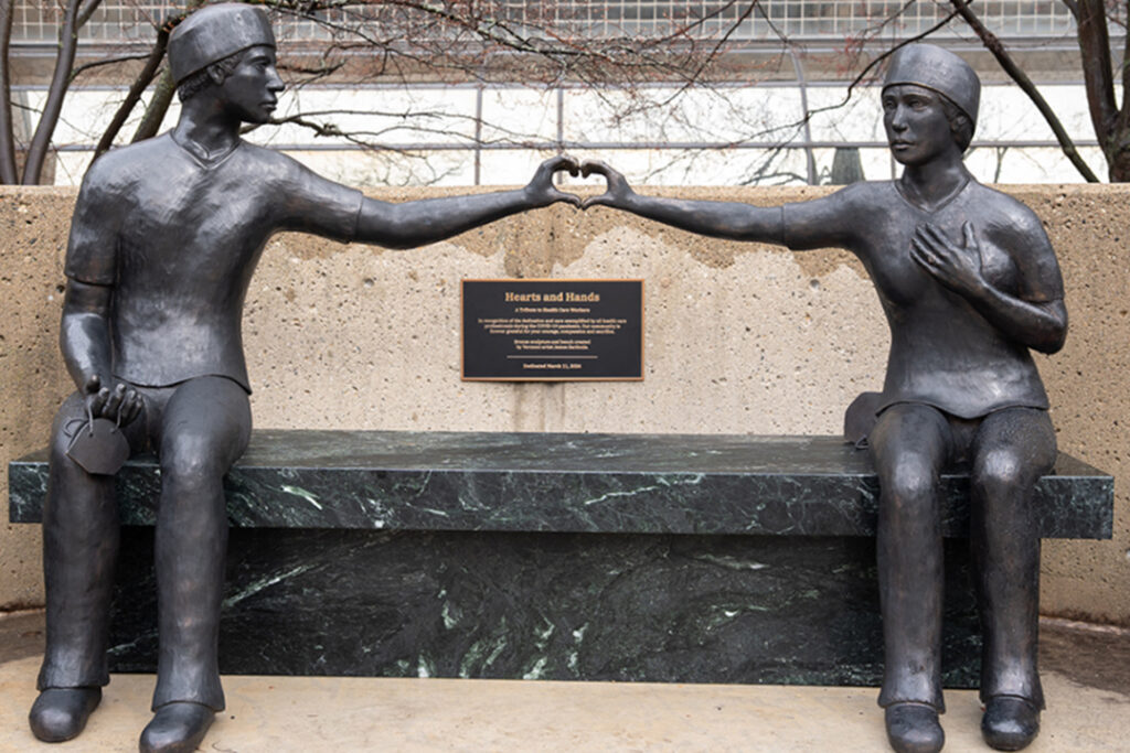 A sculpture at Michigan Medicine depicts essential workers creating a heart shape with their two hands. Statue is named Hearts and Hands and can be found in Ann Arbor, Michigan.