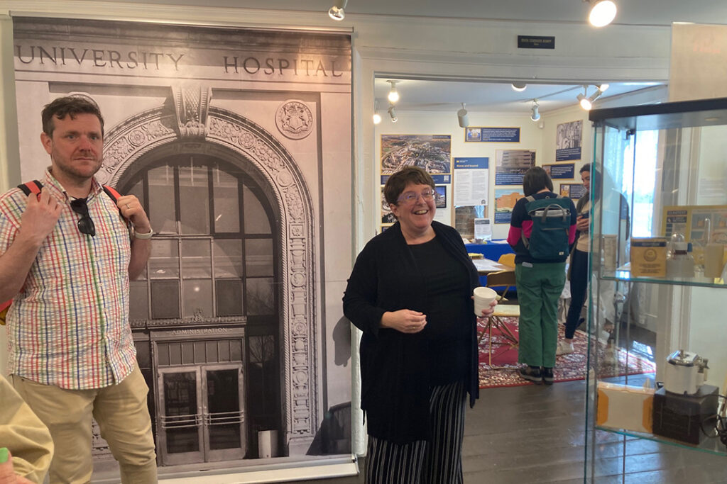 Two people stand in front of an almost life-sized photograph of the original door to the University of Michigan's Old Main Hospital in Ann Arbor, Mich.