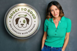 Woman in green top stands next to circular logo that reads Doggy Do Good: Pet Supplies with Purpose.