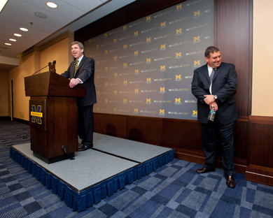 David Brandon at podium introducing Brady Hoke who stands to side