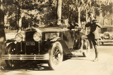 Police officer Chester Youngs alongside a car, circa 1920